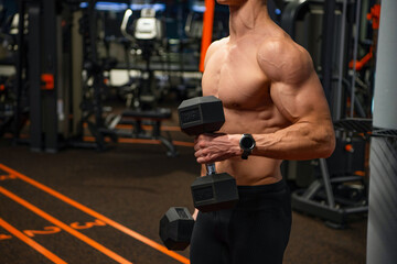 Shirtless man crop view doing biceps triceps workout with dumbbells in gym, strength training