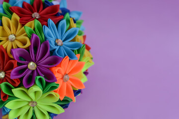 Obraz premium Ribbon flowers handmade on a pink background, satin ribbons. handmade round ball of colorful ribbon flowers. creativity concept