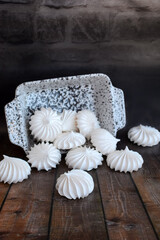 White tasty meringue is scattered on the table on a dark rustic background