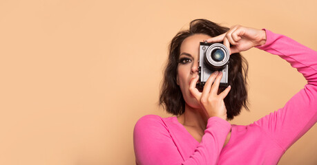 Portrait of serious woman photographer looking in camera beige background copy space, photographing