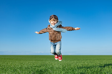 Happy child jumping outdoor in spring field