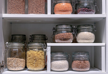 Glass jars with pasta, various cereals and grains. Foods storage concept .