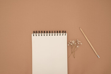 A mock-up of a close book notebook on beige background, top view