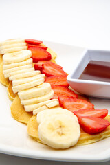 Delicious light breakfast of hotcakes with strawberries, banana and a touch of honey
