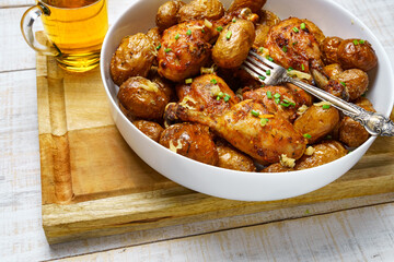 tasty lunch in rural style, healthy food - glass of beer, fried chicken meat and unpeeled roasted potatoes, chopped leeks, cooked food on a white wooden boards