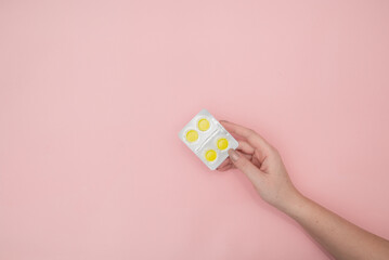 Woman holding blister with cough drops pills tablets on pink background, top view. Space for text