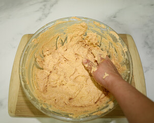 Mixing masa for tamales infused with guajillo chili sauce.