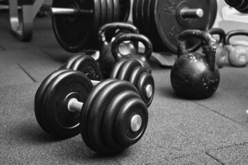 Fototapeta na wymiar Dumbbells and kettlebells on a floor. Bodybuilding equipment. Fitness or bodybuilding concept background. black and white photography