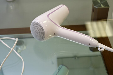 white hair dryer lies on a glass table
