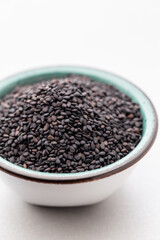 Bio natural black sesame seeds on white bowl.
