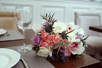 An empty glass is on the table next to the wedding bouquet. Bouquet of pink and white roses.