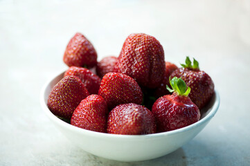 Ripe strawberries in a white bowl. Selective focus, close-up