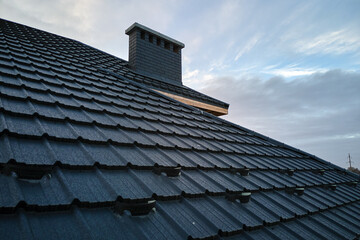 Snow guard for safety in winter on house roof top covered with ceramic shingles. Tiled covering of building