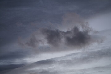 Spät abendlicher blaugrauer Himmel mit unterschiedlichen Wolken, die während eines Sturms über Land vorbeiziehen