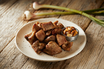 Homemade fritada a typical ecuadorian dish that consists on braised pork. It’s served on a white plate with chilli and tostado, with a traditional and wooden background 