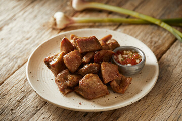Homemade fritada a typical ecuadorian dish that consists on braised pork. It’s served on a white plate with chilli and tostado, with a traditional and wooden background 
