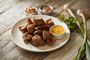 Homemade fritada a typical ecuadorian dish that consists on braised pork. It’s served on a white plate with chilli and tostado, with a traditional and wooden background 