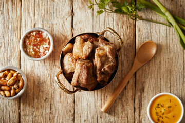 Homemade fritada a typical ecuadorian dish that consists on braised pork. It’s served on a white plate with chilli and tostado, with a traditional and wooden background 