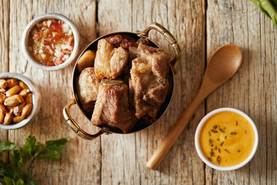 Homemade fritada a typical ecuadorian dish that consists on braised pork. It&rsquo;s served on a white plate with chilli and tostado, with a traditional and wooden background 