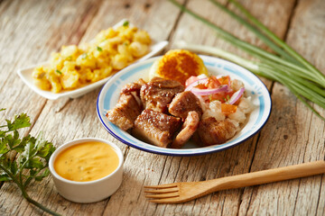 Homemade fritada a typical ecuadorian dish that consists on braised pork. It’s served on a white plate with motepillo and with a traditional and wooden background 