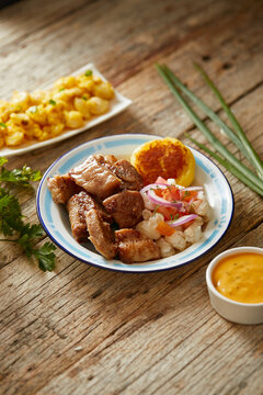 Homemade fritada a typical ecuadorian dish that consists on braised pork. It&rsquo;s served on a white plate with motepillo and with a traditional and wooden background 
