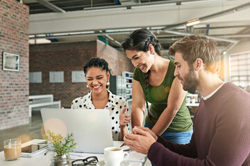 Easier problem solving thanks to technology. Shot of a team of colleagues using a laptop together in a modern office.