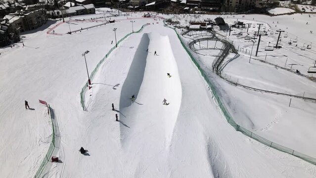 2022 - Excellent aerial view of people skiing and snowboarding on a half-pipe at Steamboat Springs, Colorado.