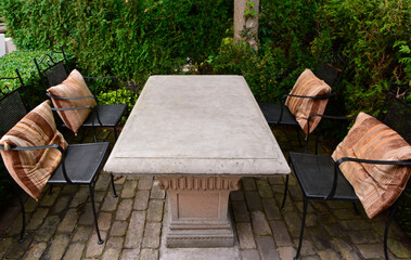 kamienny stół w ogrodzie z metalowymi krzesłami, relaxation area in the garden - obrazy, fototapety, plakaty