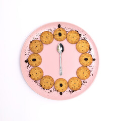 Some cookies served on a pink plate with coffee sprinkles with a teaspoon in the center on a white...