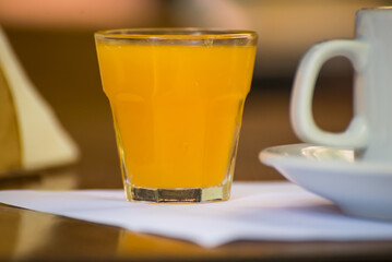orange juice in a glass next to a ham and cheese waffle