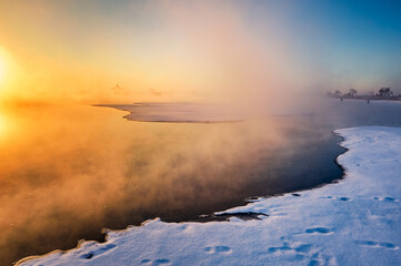 The  oil sucking machines at lakeside sunrise in Daqing oil fields, China.