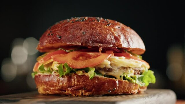 Tasty burger close-up, cooked juicy sandwich, fast food concept, recipe of preparing homemade hamburger with meat and fresh vegetables.