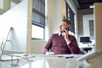 Im always up for a little business talk. Shot of a businessman talking on his cellphone while sitting at his desk.