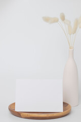 greeting card mock up. decoration with white flower, Front view, Blank paper card on a wood plate and white background