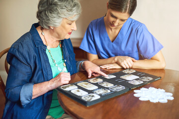 Shes got plenty of photos to share. Shot of a resident and a nurse looking through a photo album.