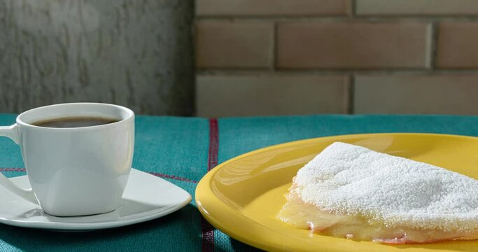 Cup of coffee next to tapioca with cheese and ham, dusty air_side view.