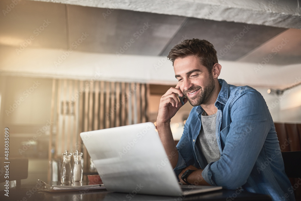 Poster the perfect place for some productivity. shot of a handsome young man using a laptop and phone in a 