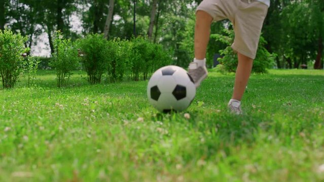 Unknown boy legs making soccer exercise closeup. Son training football with dad.