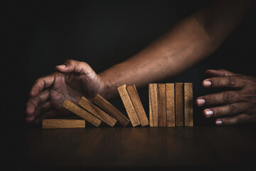 Close-up hands prevent wooden block falling domino concepts of financial risk management and...