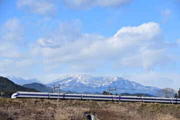 冠雪の日光連山を背景に走る東武鉄道100系特急電車（スペーシア）