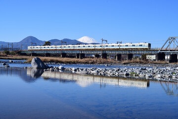 冠雪の富士山を背景に酒匂川橋梁を渡る小田急電鉄8000形電車