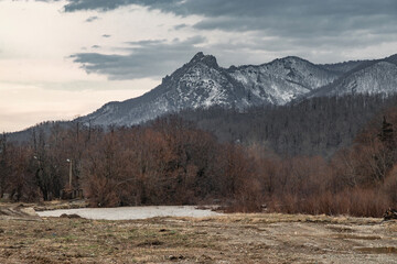 View of Indyuk Mountain, covered with snow 859 meters high, on a cloudy winter day in the foothills of the Caucasus. A forest with little snow in winter on a cloudy day.