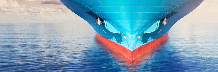 Front view of large blue container cargo ship in ocean waters. Performing cargo export and import...
