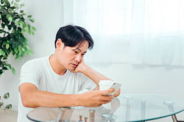 部屋でスマホを見る男性（体調不良）
