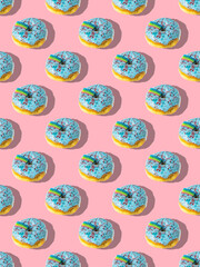 A repeating pattern of blue donuts with a rainbow on a pink background