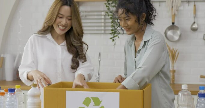 Happy lesbians woman at home, Two Beautiful woman putting plastic bottles into donate box at home. Donation, Volunteer and Lifestyle concept.