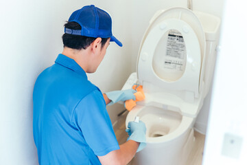 トイレの掃除をする作業着の男性
