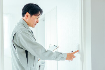 Naklejka na ściany i meble 電気をチェックする作業服の男性 