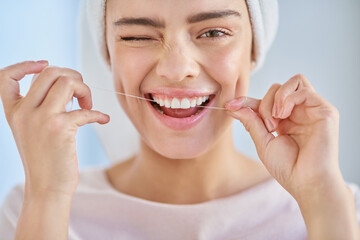 Dont forget to floss. Cropped portrait of a beautiful young woman flossing her teeth in the...