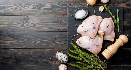Sliced chicken thighs with skin on a cutting board. Black wooden background. Top view. Copy space